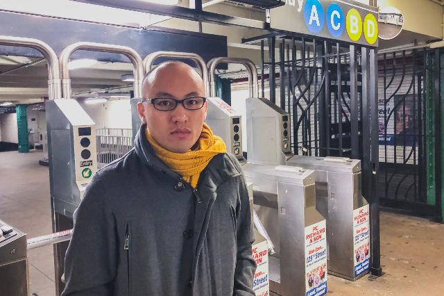 John Tran stands in front of the subway turnstile at the 125th Street station where he was wrongly stopped by police officers for fare evasion on December 26, 2018.